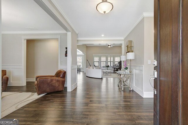 entryway with a decorative wall, ornamental molding, a ceiling fan, and dark wood finished floors