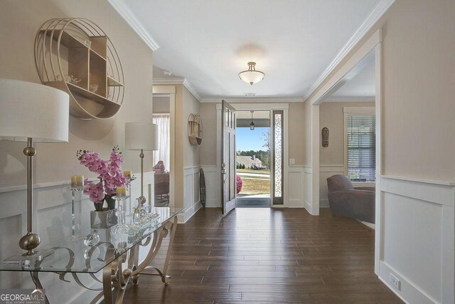 entrance foyer with dark wood-type flooring, crown molding, a decorative wall, and wainscoting