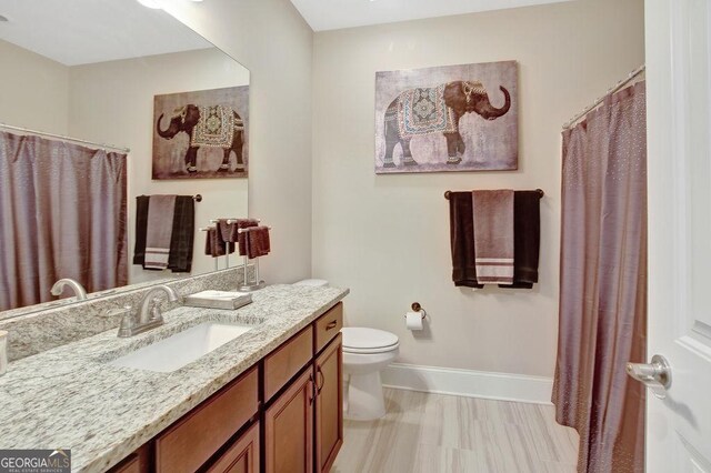 full bathroom with toilet, vanity, and baseboards