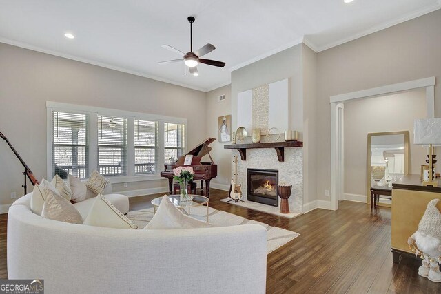 living area with ornamental molding, a ceiling fan, wood finished floors, and a fireplace with flush hearth