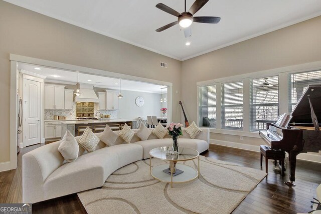 living area featuring visible vents, baseboards, ornamental molding, a ceiling fan, and dark wood-style floors