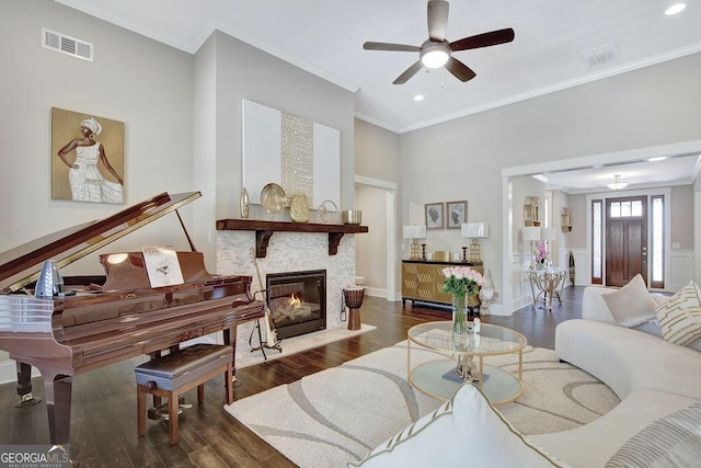 living room with ornamental molding, visible vents, a ceiling fan, and wood finished floors