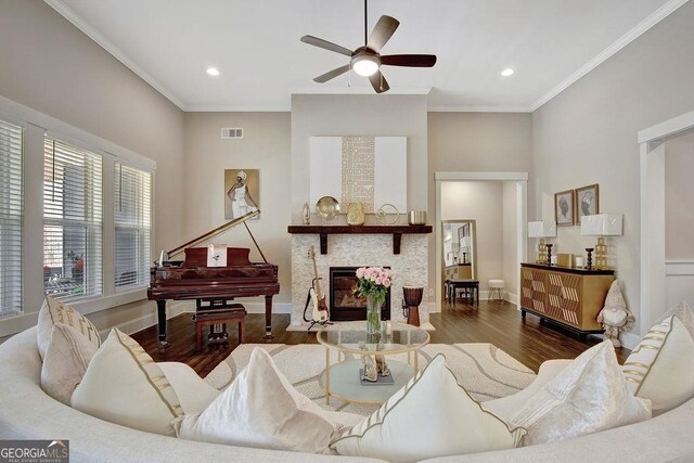 living room with crown molding, ceiling fan, a glass covered fireplace, visible vents, and wood finished floors