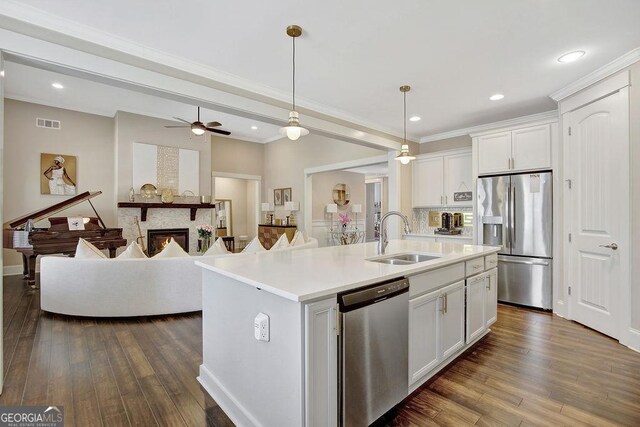 kitchen featuring an island with sink, light countertops, white cabinets, stainless steel appliances, and a sink