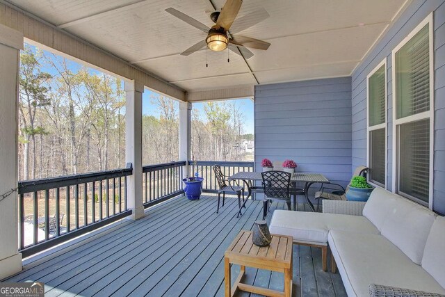 wooden deck with an outdoor living space, outdoor dining space, and a ceiling fan