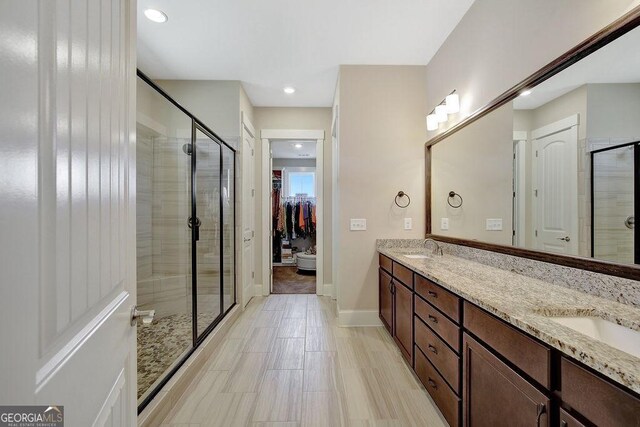 full bath featuring a sink, double vanity, and a stall shower