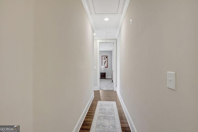 corridor with dark wood-style flooring, baseboards, attic access, and crown molding