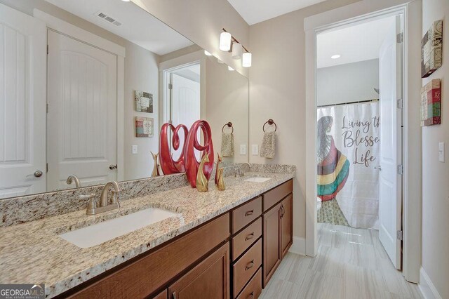 bathroom featuring baseboards, double vanity, a sink, and visible vents