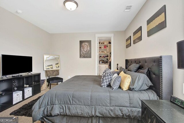 carpeted bedroom featuring visible vents, a walk in closet, and a closet
