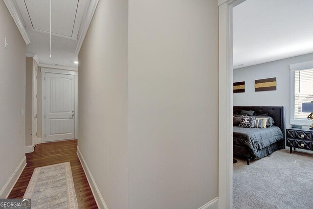 corridor featuring crown molding, baseboards, attic access, and wood finished floors