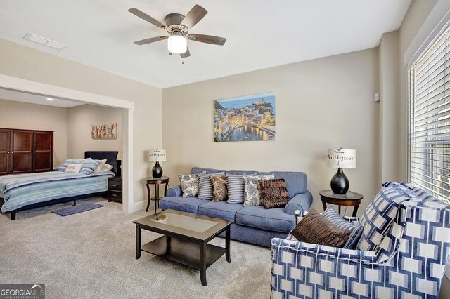 living area featuring baseboards, visible vents, light colored carpet, and a ceiling fan