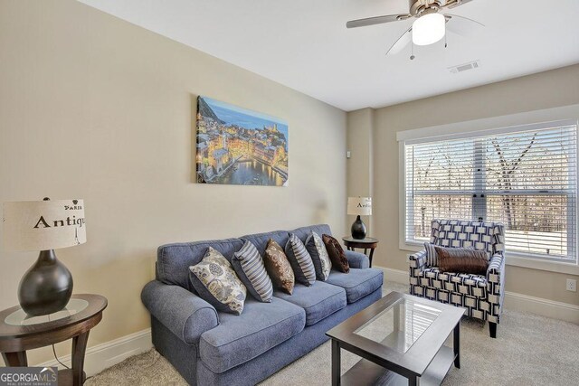 carpeted living area featuring baseboards, a ceiling fan, and visible vents