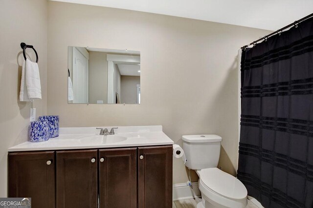 full bath with toilet, a shower with shower curtain, vanity, and baseboards