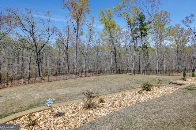 view of yard featuring a wooded view and a fenced backyard