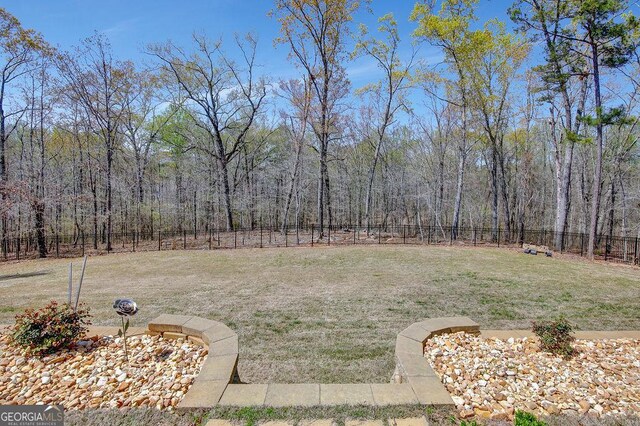 view of yard with a fenced backyard and a view of trees