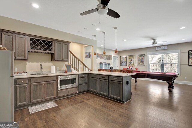 kitchen with a sink, freestanding refrigerator, a ceiling fan, a peninsula, and stainless steel microwave