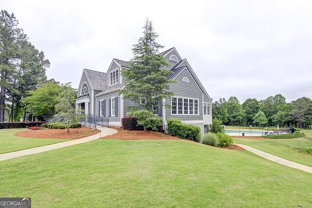 view of front of home with an outdoor pool and a front yard