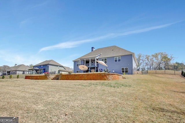 rear view of house with a yard, fence, and a chimney