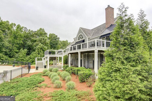rear view of property with fence, stairway, a wooden deck, and a chimney