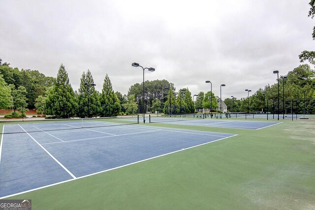 view of tennis court featuring community basketball court and fence