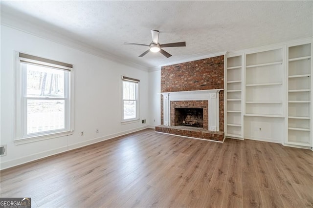 3775 Belle Glade Trl, Snellville, GA 30039 - unfurnished living room with ceiling fan, a textured ceiling, wood finished floors, ornamental molding, and a brick fireplace