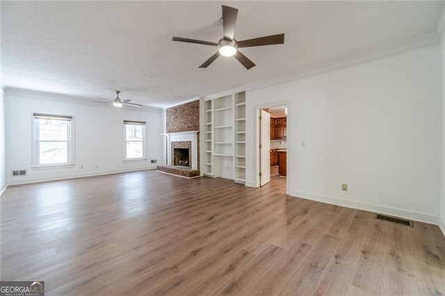 3775 Belle Glade Trl, Snellville, GA 30039 - unfurnished living room featuring a ceiling fan, wood finished floors, a brick fireplace, crown molding, and built in shelves