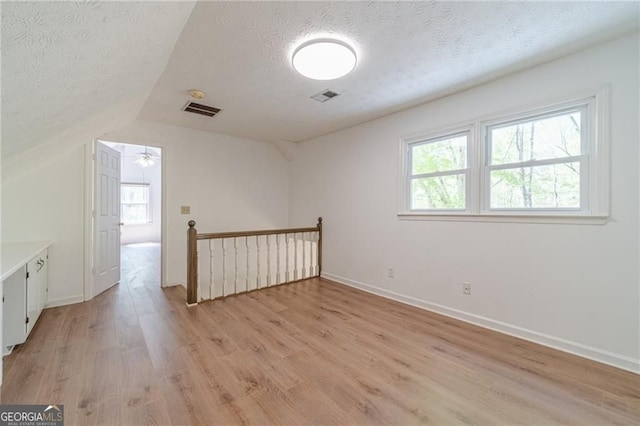 3775 Belle Glade Trl, Snellville, GA 30039 - unfurnished room with a textured ceiling, light wood-style flooring, vaulted ceiling, and healthy amount of natural light