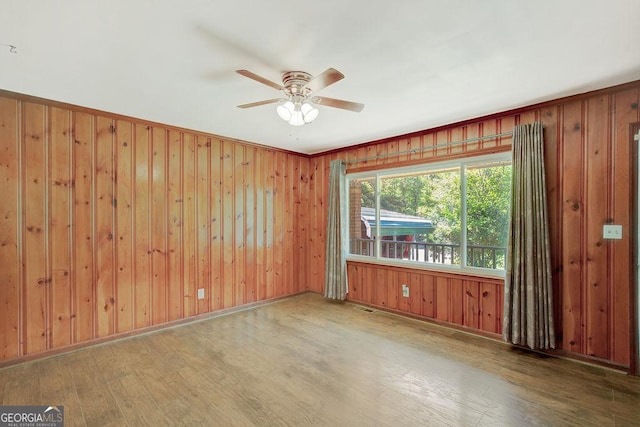 spare room with wood finished floors, ceiling fan, and wooden walls