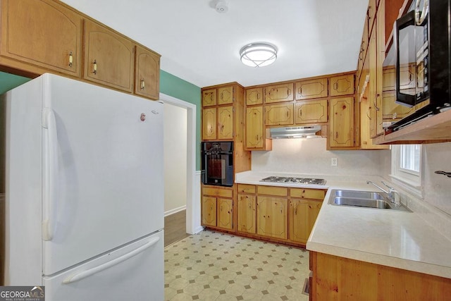 kitchen featuring light floors, black appliances, under cabinet range hood, light countertops, and a sink