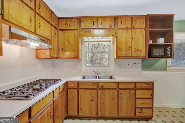 kitchen featuring a wealth of natural light, under cabinet range hood, stainless steel gas stovetop, and a sink