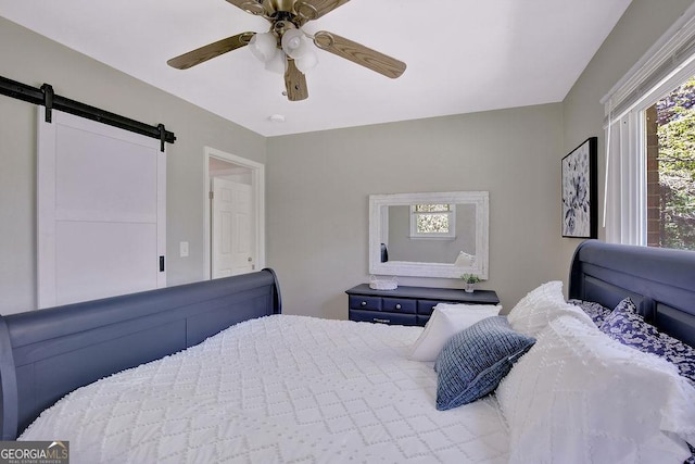 bedroom featuring ceiling fan and a barn door