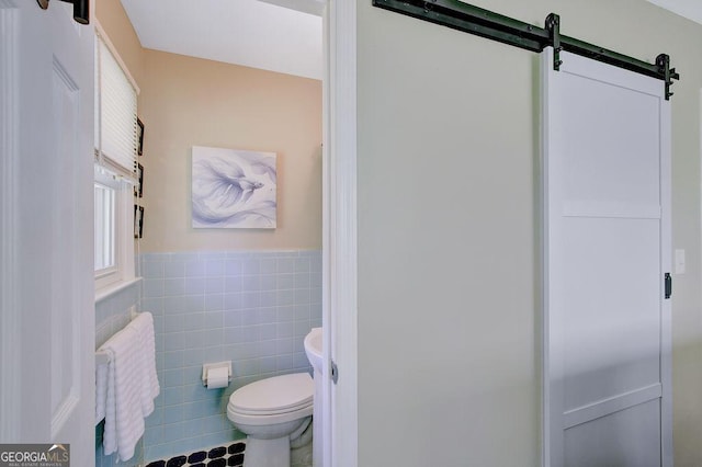 bathroom with tile patterned flooring, wainscoting, tile walls, and toilet