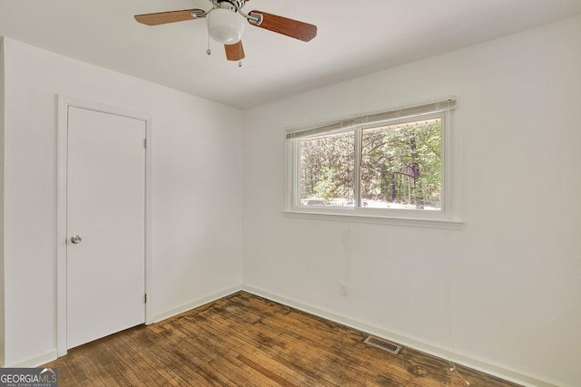 spare room featuring dark wood-type flooring, visible vents, baseboards, and a ceiling fan
