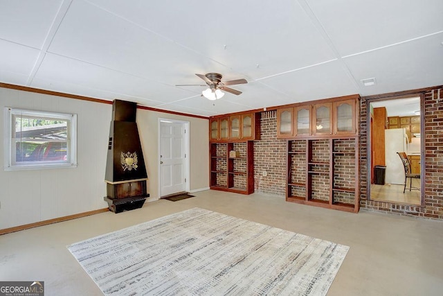 interior space featuring brick wall, baseboards, and a ceiling fan