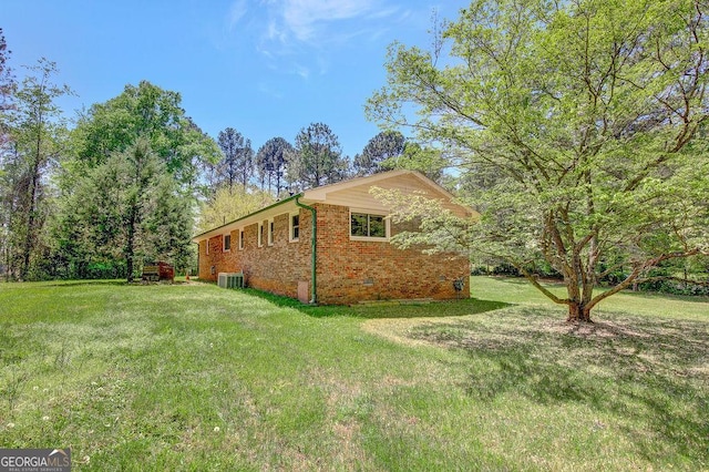 view of side of home featuring central AC, brick siding, and a lawn
