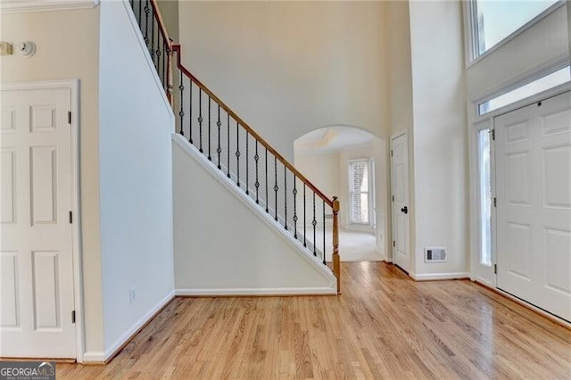 entryway featuring stairway, arched walkways, a high ceiling, and wood finished floors