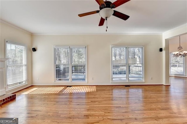 unfurnished living room with baseboards, wood finished floors, ceiling fan with notable chandelier, and crown molding