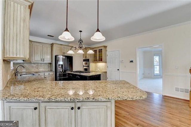 kitchen featuring fridge with ice dispenser, a sink, crown molding, light stone counters, and double oven