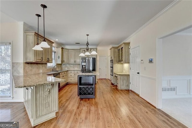kitchen featuring light stone countertops, a sink, visible vents, a peninsula, and stainless steel fridge with ice dispenser