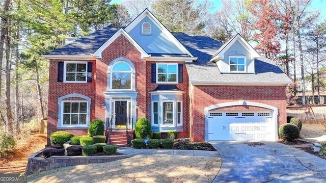 colonial house featuring concrete driveway, brick siding, and a garage