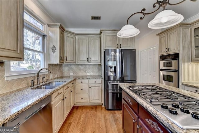 kitchen with stainless steel appliances, a wealth of natural light, light wood finished floors, and a sink