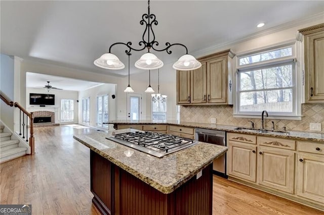 kitchen with light wood-style flooring, stainless steel appliances, a brick fireplace, a sink, and open floor plan
