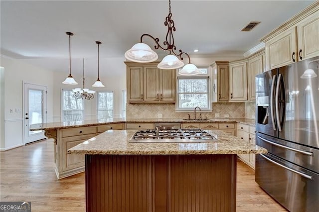 kitchen with a sink, appliances with stainless steel finishes, visible vents, cream cabinetry, and a peninsula