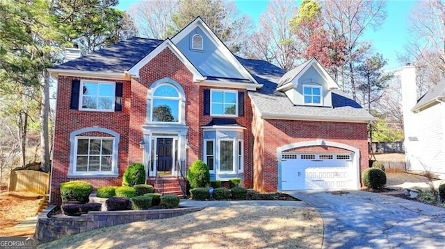 view of front of house featuring driveway, a chimney, an attached garage, and brick siding