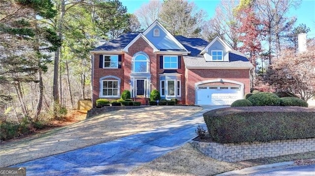 view of front of home featuring driveway, brick siding, and a garage