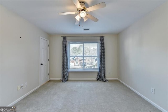 carpeted spare room featuring visible vents, a ceiling fan, and baseboards