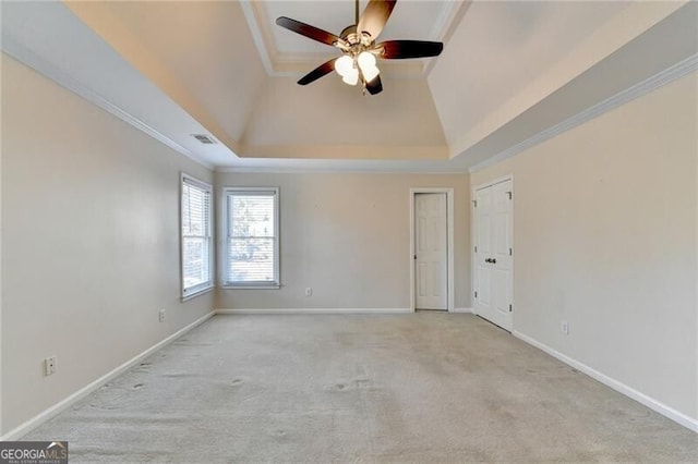 carpeted spare room with ornamental molding, a ceiling fan, visible vents, and a tray ceiling