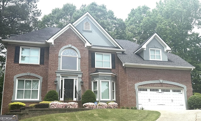 view of front of home with a front yard, roof with shingles, driveway, and brick siding
