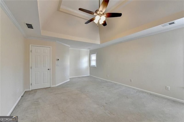 carpeted empty room with crown molding, a ceiling fan, visible vents, and a raised ceiling