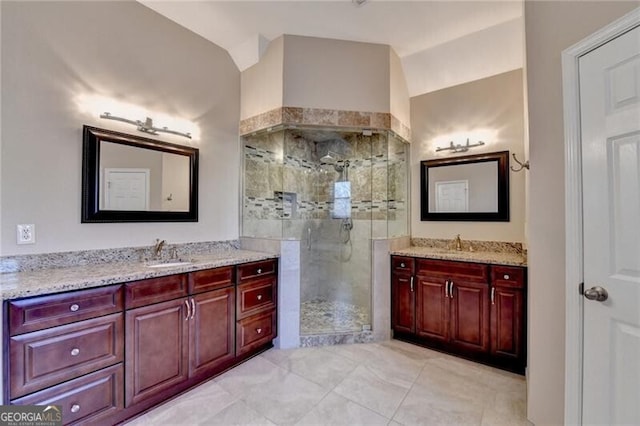 bathroom with lofted ceiling, a shower stall, a sink, two vanities, and tile patterned floors